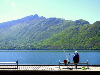 Rear view of man and woman standing by sea against clear sky