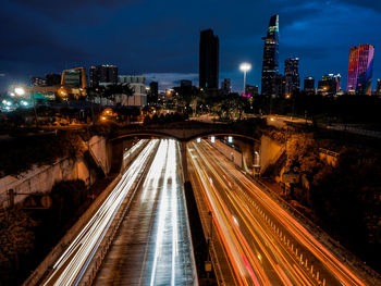 High angle view of light trails on street amidst buildings at night