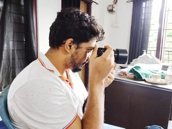 Side view of young man sitting at home