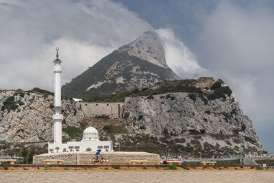 Mosque against cloudy sky and hills 