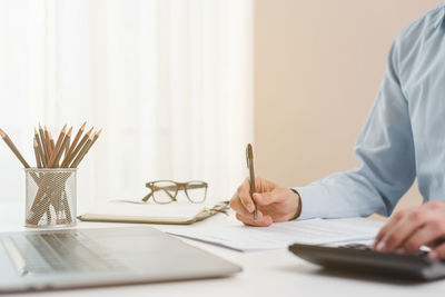 Midsection of businessman working on table