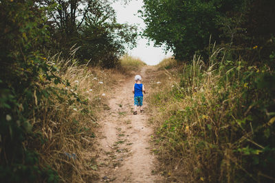 Rear view of boy walking on footpath