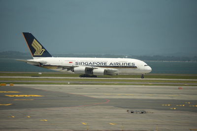 Airplane flying over airport runway against sky