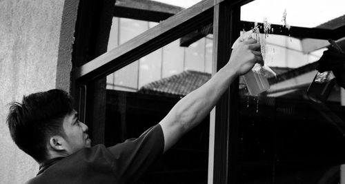 Portrait of young man holding glass window