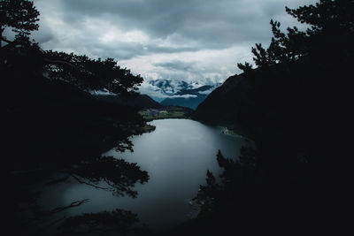 Scenic view of lake by silhouette trees against sky