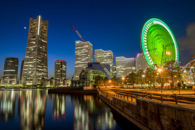 Illuminated modern buildings in city against sky at night