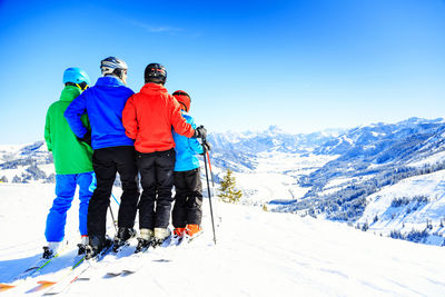 People skiing on snowcapped mountains against sky