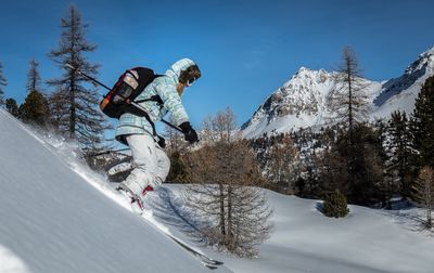 Side view of girl skiing on snowcapped mountain against sky