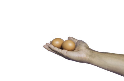 Close-up of hand holding bread against white background