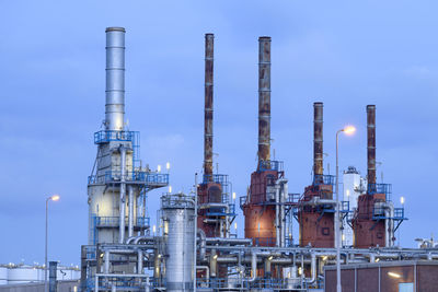 Low angle view of illuminated factory against sky at dusk