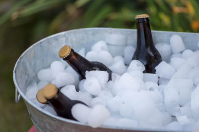 Beer bottles sitting in an ice filled tub outside at backyard summer party