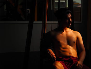 Shirtless young man sitting in gym