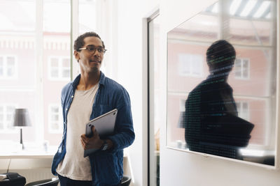 Computer hacker looking at code on television screen while standing in creative office