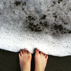 Low section of man standing on sand