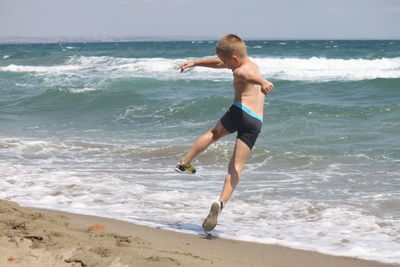 Full length of shirtless man at beach