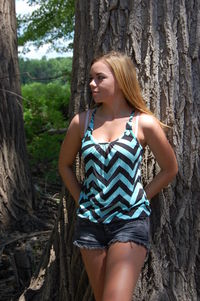 Young woman leaning on tree trunk