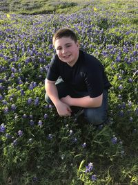 High angle portrait of smiling boy crouching on field