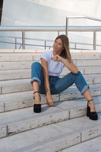 Full length of young woman sitting on staircase