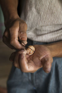 Midsection of man cutting nut