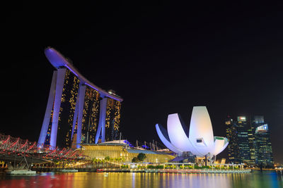 Illuminated modern buildings in city against sky at night