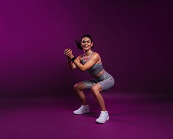 Portrait of young woman exercising against black background