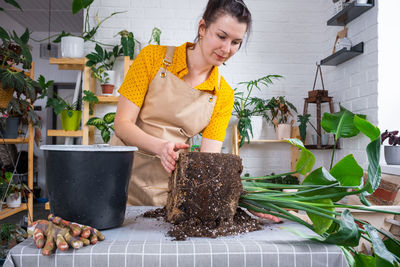 Portrait of smiling young woman holding potted plant