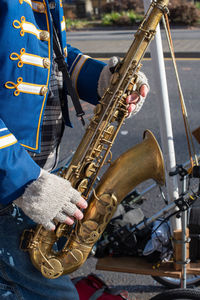 Midsection of musician playing saxophone on road 