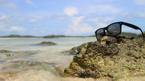 Close-up of sunglasses on rock at shore