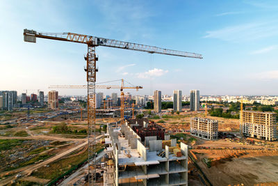 Crane at construction site against buildings in city