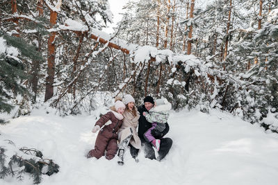 Dad and mom and daughters have fun in the snowy forest. high quality photo