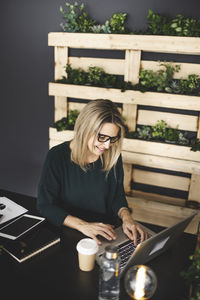 Midsection of woman using mobile phone while sitting on table