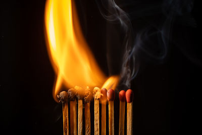 Close-up of burning candles against black background