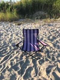 Empty chairs on sand at beach