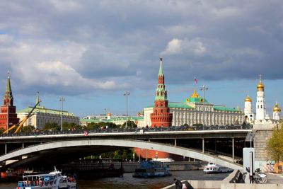 Bridge over river in city against cloudy sky