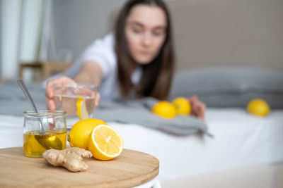 Woman holding glass of water while sitting at home