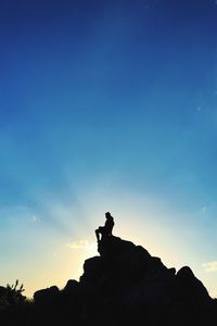 Low angle view of silhouette man against blue sky