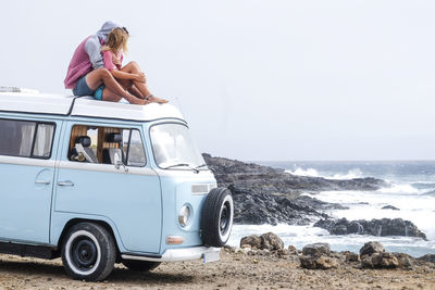 Spain, tenerife, young couple in love relaxing on car roof of van