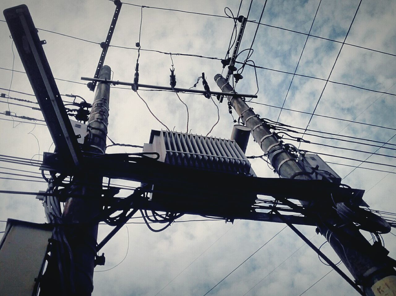 low angle view, sky, power line, built structure, architecture, building exterior, cable, electricity, electricity pylon, power supply, technology, silhouette, cloud - sky, connection, fuel and power generation, outdoors, day, power cable, construction site, building