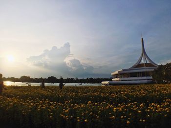 Building by field against sky during sunset