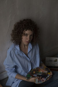 Young woman looking away while sitting on wall