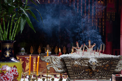 Candles and incense sticks burning against temple