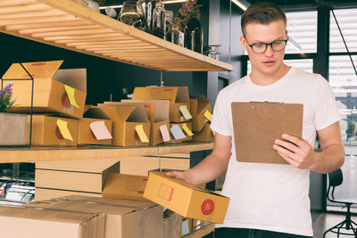 Man holding cardboard box and clipboard in creative office