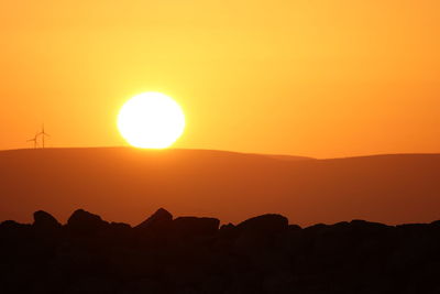 Scenic view of silhouette mountains against orange sky