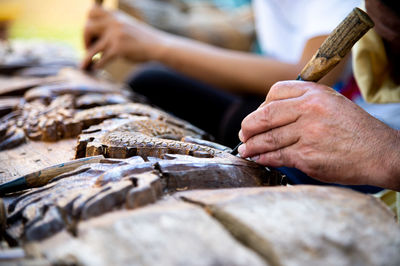 Midsection of artists carving design on wood