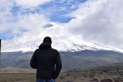 Rear view of man standing on snow covered mountain