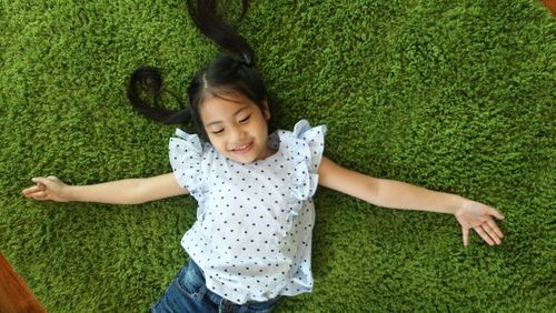 High angle view of smiling girl lying on grass