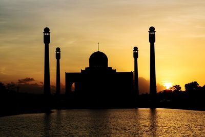 Silhouette of building against cloudy sky during sunset