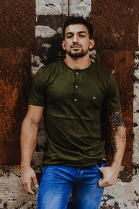 Portrait of young man standing against wall