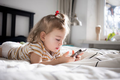 High angle view of cute baby girl lying on bed at home