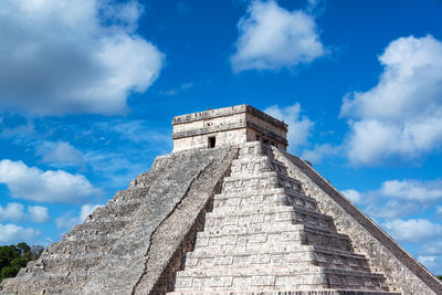Low angle view of kukulkan pyramid against blue sky during sunny day